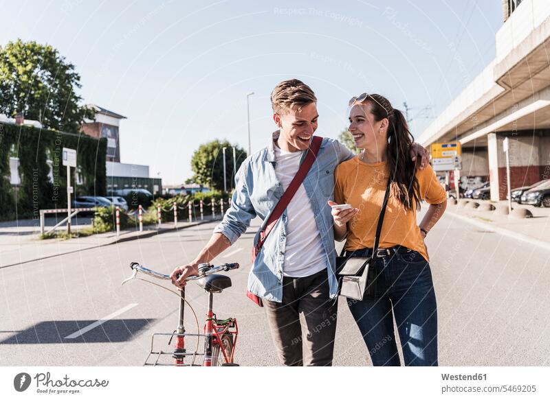 Glückliches junges Paar geht auf der Straße in der Stadt Farbaufnahme Farbe Farbfoto Farbphoto Außenaufnahme außen draußen im Freien Tag Tageslichtaufnahme