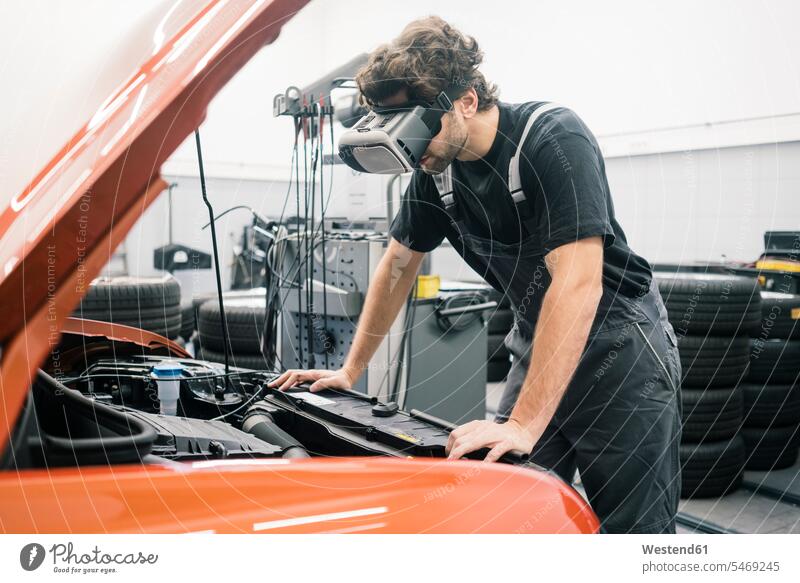 Automechaniker mit VR-Brille in einer Werkstatt bei der Arbeit am Auto Job Berufe Berufstätigkeit Beschäftigung Jobs Gewerbe industriell Industrien Monteur KFZ