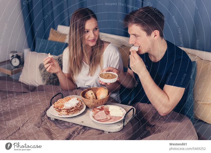 Junges Paar beim Frühstück im Bett Pärchen Paare Partnerschaft frühstücken Betten entspannt entspanntheit relaxt Mensch Menschen Leute People Personen Mahlzeit