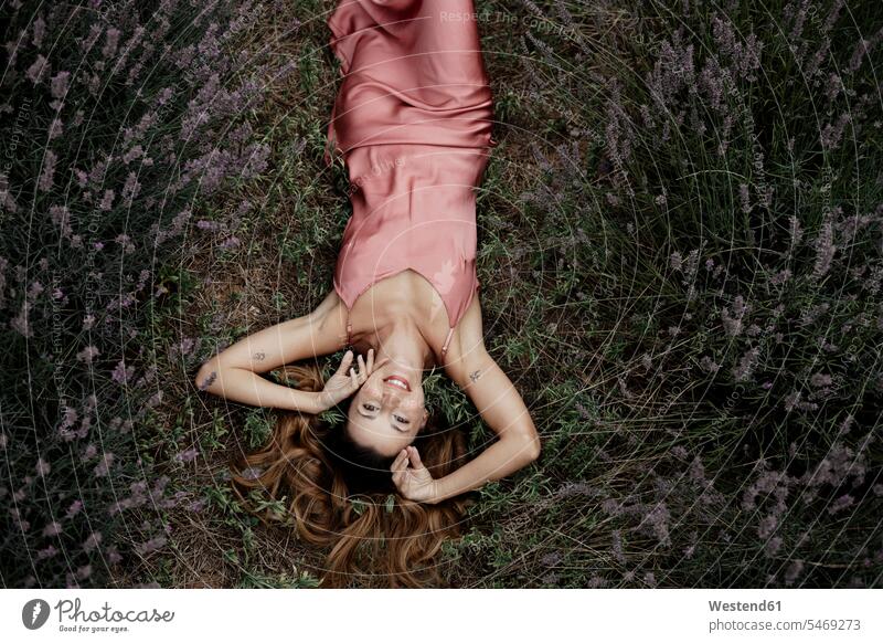 Frau im Lavendelfeld liegend Kleider entspannen relaxen freuen geniessen Genuss Glück glücklich sein glücklichsein zufrieden lilafarben violett rosafarben liegt