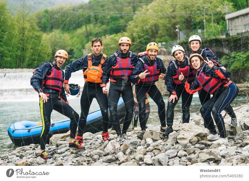 Gruppe spielerischer Freunde bei einem Rafting-Kurs, die am Boot posieren Kameradschaft begeistert Enthusiasmus enthusiastisch Überschwang Überschwenglichkeit