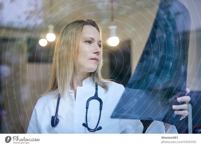 Ärztin schaut auf Röntgenbild hinter Fensterscheibe Aerztin Ärztinnen Doktorinnen Aerztinnen Frau weiblich Frauen Roentgenbild Roentgenbilder Röntgenbilder