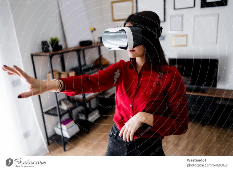 Junge Frau verwendet VR-Brille zu Hause geschäftlich Geschäftsleben Geschäftswelt Geschäftsperson Geschäftspersonen Businessfrau Businessfrauen Businesswoman