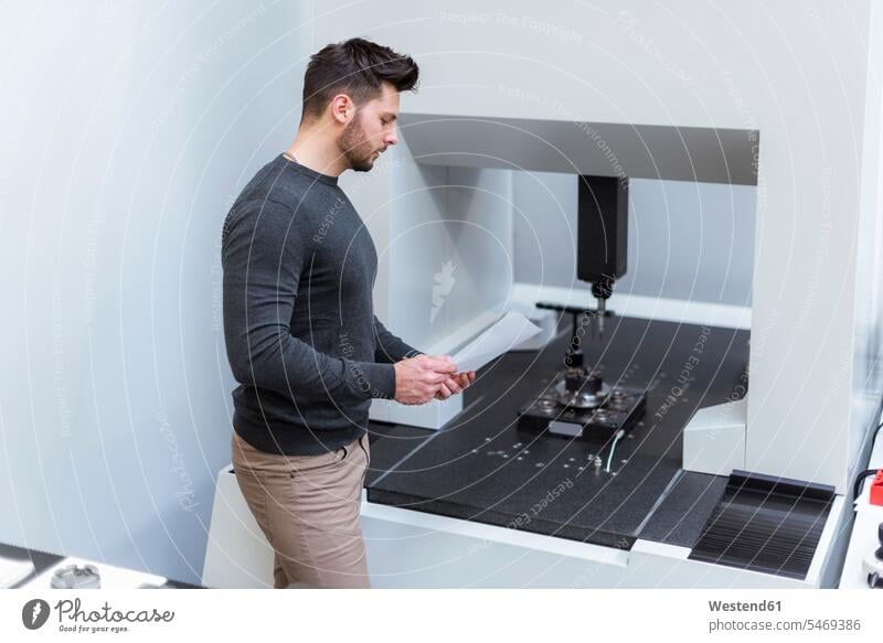 Mann mit Papierprüfmaschine in moderner Fabrik Männer männlich Maschine Maschinen Fabriken untersuchen prüfen Erwachsener erwachsen Mensch Menschen Leute People