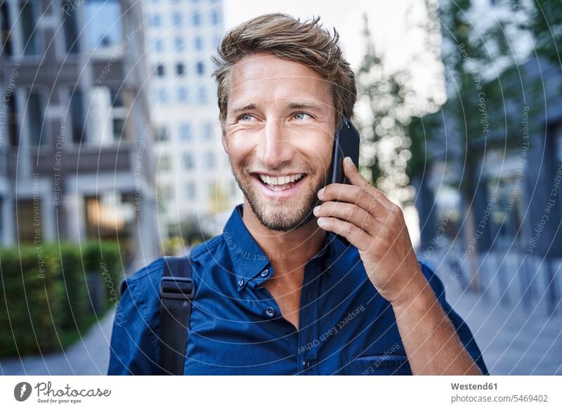 Porträt eines glücklichen jungen Geschäftsmannes am Telefon in der Stadt geschäftlich Geschäftsleben Geschäftswelt Geschäftsperson Geschäftspersonen