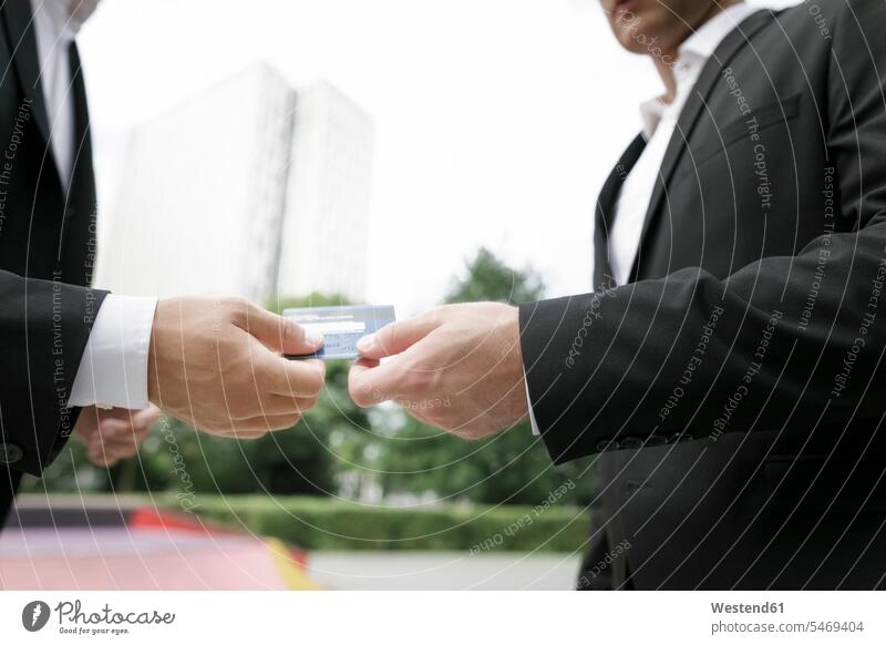 Zwei Geschäftsleute bei der Übergabe der Kreditkarte Geschäftsmann Businessmann Businessmänner Geschäftsmänner EC-Karte Kreditkarten Mann Männer männlich geben