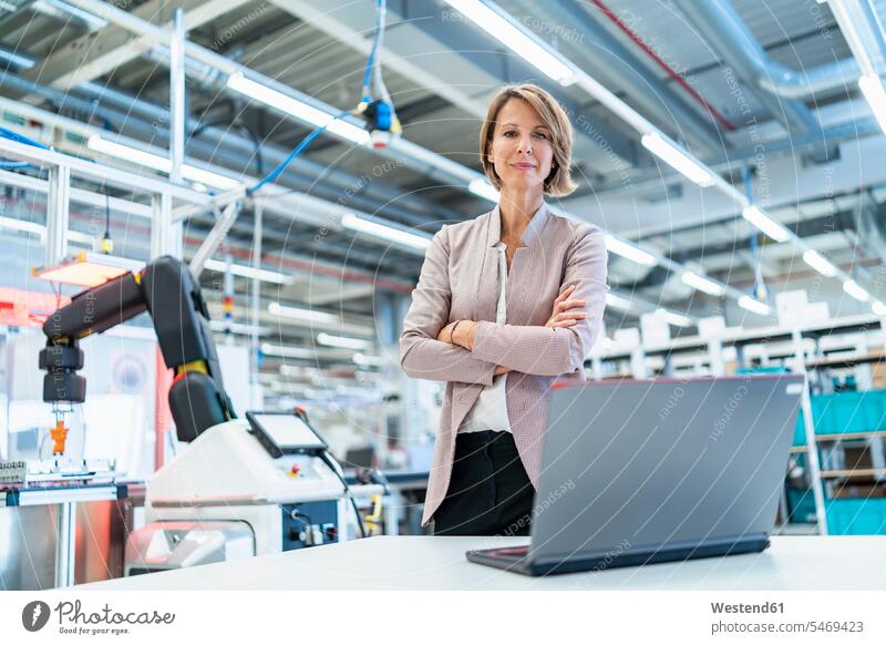 Porträt einer selbstbewussten Geschäftsfrau mit Laptop in einer modernen Fabrikhalle Leute Menschen People Person Personen Europäisch Kaukasier kaukasisch 1 Ein