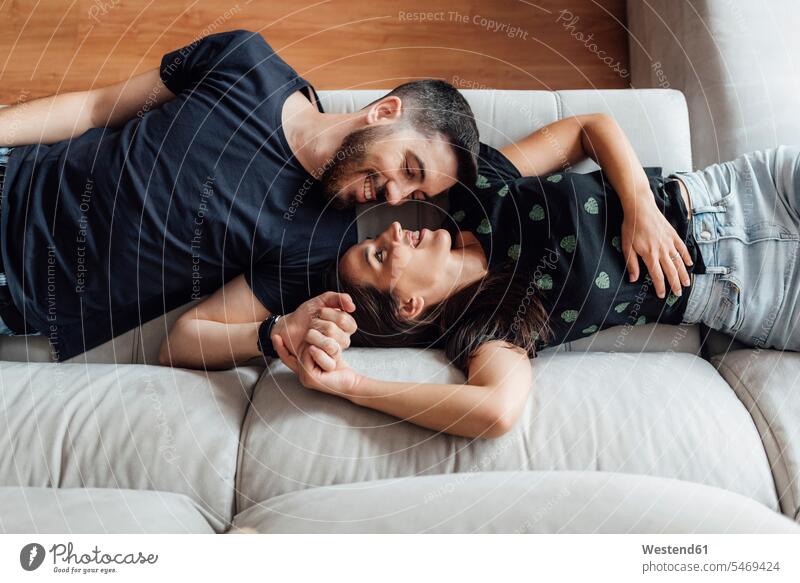 Paar entspannt im Liegen auf dem Sofa zu Hause Farbaufnahme Farbe Farbfoto Farbphoto Innenaufnahme Innenaufnahmen innen drinnen Tag Tageslichtaufnahme