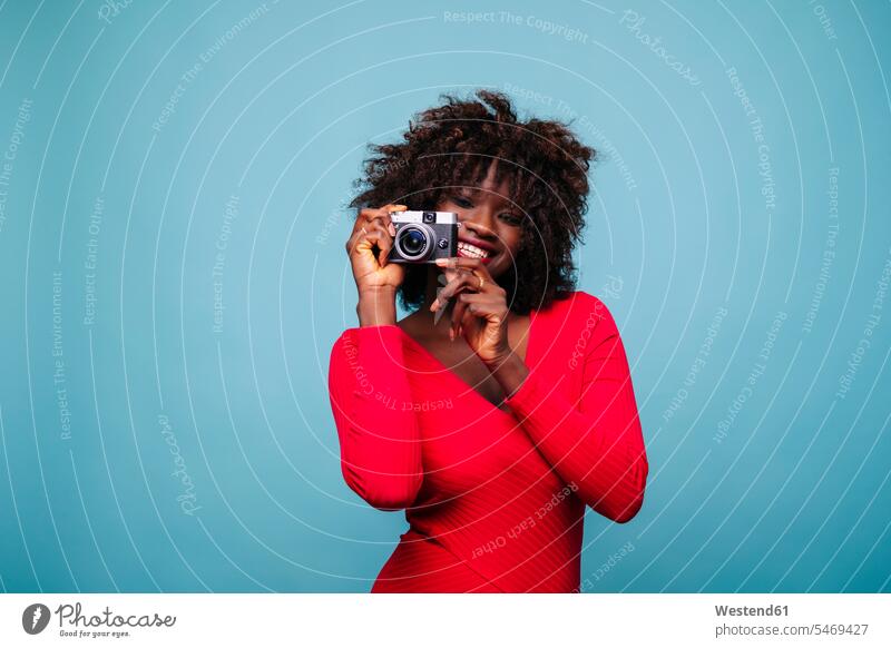 Porträt einer glücklichen jungen Frau, die eine Vintage-Kamera im Studio hält Fotografen Photograph Photographen Leute Menschen People Person Personen gelockt