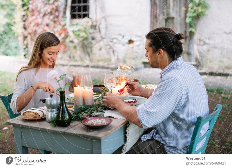 Paar mit einer romantischen Mahlzeit bei Kerzenschein neben einer Hütte Mahlzeiten Essen Speise Speisen Pärchen Paare Partnerschaft Häuschen Kate Kerzenlicht