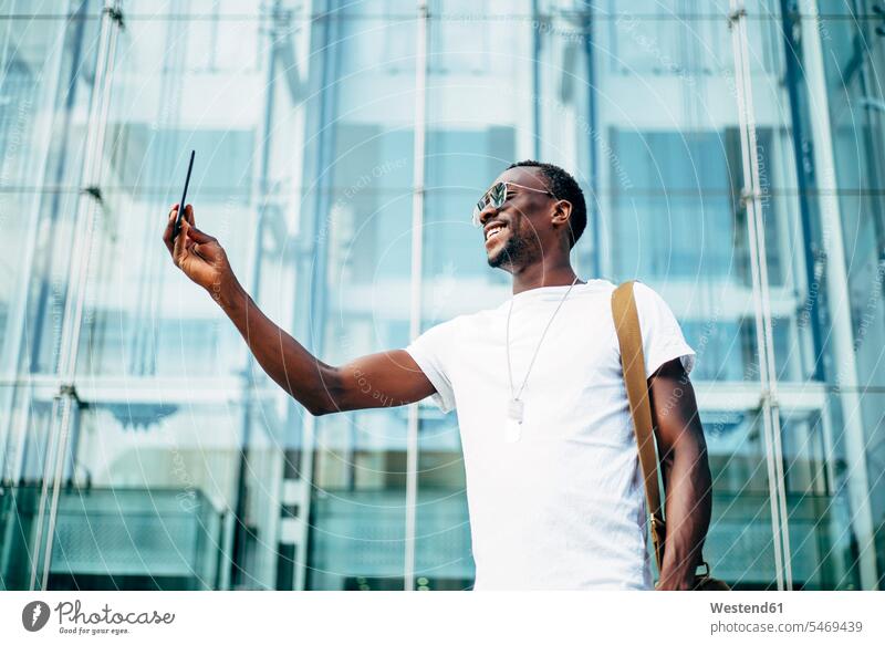 Junger Mann benutzt Mobiltelefon in der Stadt Leute Menschen People Person Personen Afrikanisch Afrikanische Abstammung dunkelhäutig Farbige Farbiger Schwarze 1
