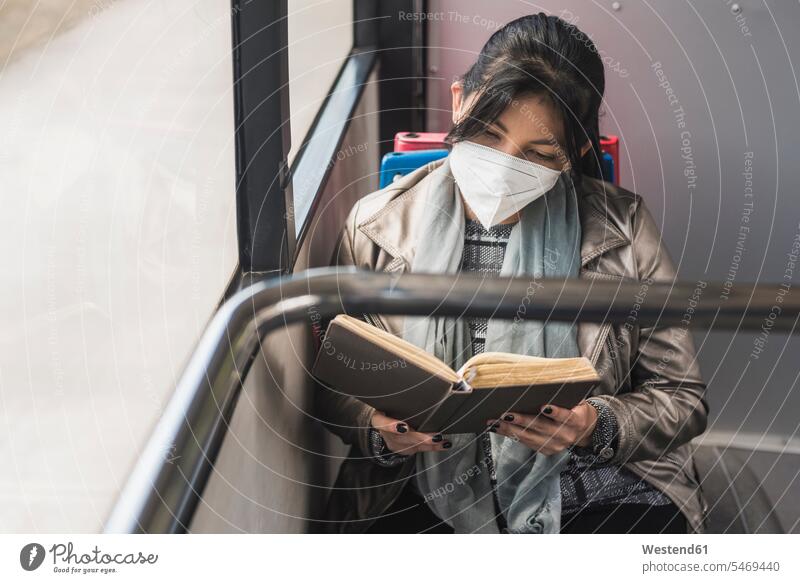 Frau mit Schutzmaske beim Lesen von Büchern im Bus Farbaufnahme Farbe Farbfoto Farbphoto Fahrzeuginnenraum differenzierter Fokus Vorderansicht Frontalansicht