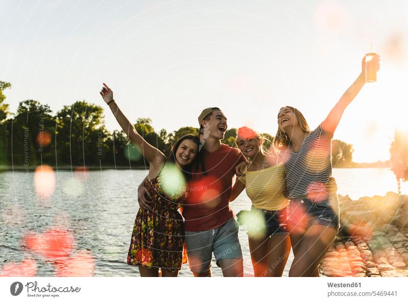 Gruppe glücklicher Freunde amüsiert sich bei Sonnenuntergang in einem Fluss Glück glücklich sein glücklichsein Spaß Spass Späße spassig Spässe spaßig Fluesse