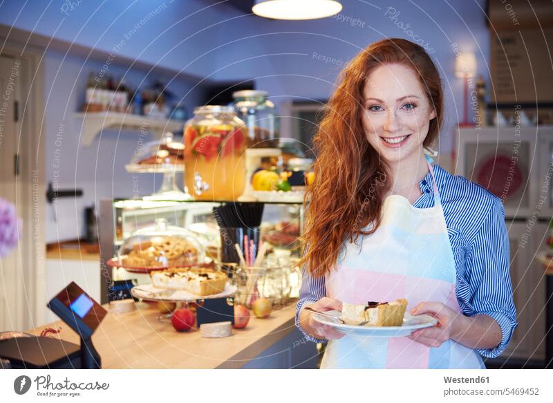 Porträt einer lächelnden jungen Frau, die in einem Cafe Kuchen serviert bedienen weiblich Frauen Portrait Porträts Portraits Kaffeehaus Bistro Cafes Café Cafés