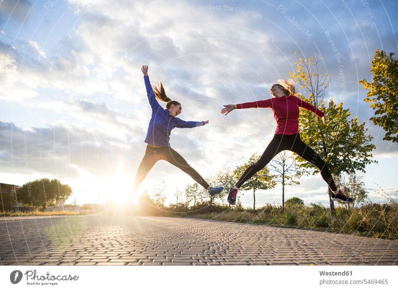 Junge Frauen haben Spaß und springen im Park, gegen Morgensonne früh Frühe begeistert Enthusiasmus enthusiastisch Überschwang Überschwenglichkeit freuen