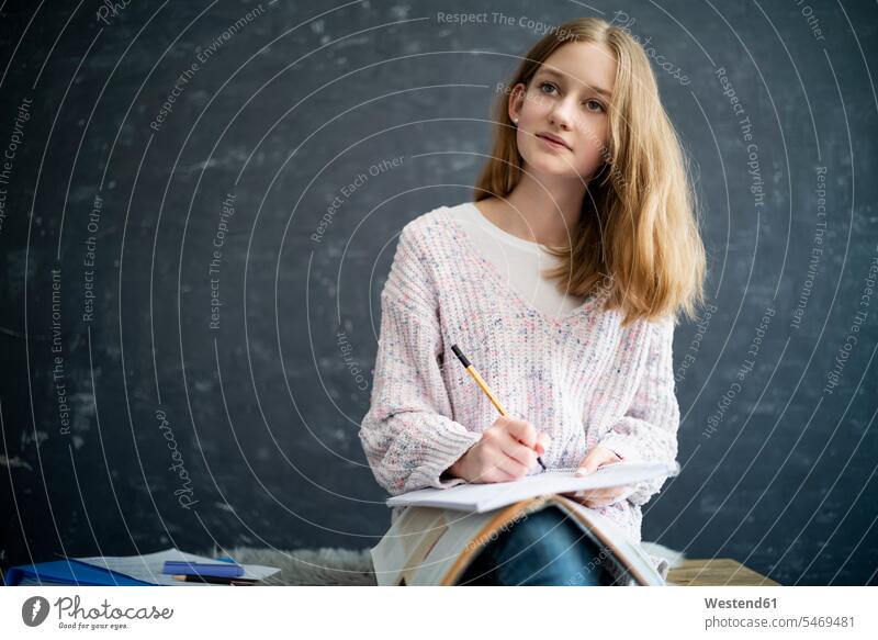 Mädchen lernt zu Hause, schreibt im Schulheft Zuversicht eine Person 12-13 Jahre Portrait lernen Hausunterricht Zuhause Deutschland Innenaufnahme nachdenken