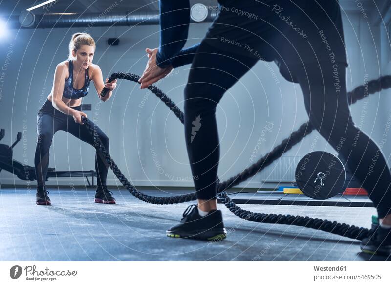 Athletische Frau beim Battlerope-Training mit Personal Trainer im Fitnessstudio Übung Uebung Übungen Uebungen Seil Seile Uebungsleiter Übungsleiter weiblich