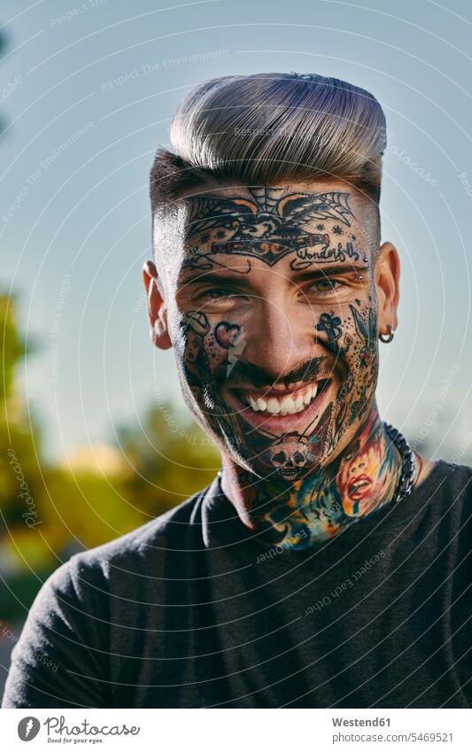 Porträt eines lächelnden tätowierten jungen Mannes im Freien Portrait Porträts Portraits Männer männlich Tattoo Tätowierungen Tatoos Taetowierung Tattoos