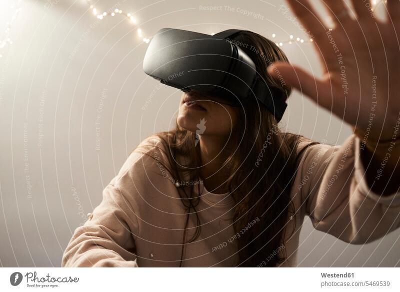 Junge Frau mit VR-Headsets beim Spielen auf dem Sofa zu Hause in der Nacht Virtual Reality Virtuelle Realität Virtual Reality Brille Virtual-Reality-Brille