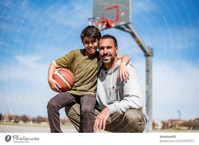 Porträt von glücklichen Vater und Sohn mit Basketball im Freien Glück glücklich sein glücklichsein lächeln umarmen Umarmung Umarmungen Arm umlegen Portrait