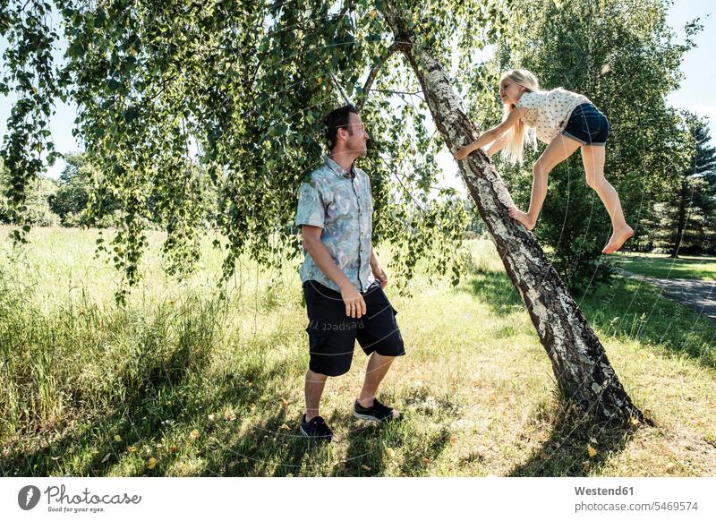 Vater beobachtet Tochter beim Klettern auf einen Birkenstamm im Park Leute Menschen People Person Personen Europäisch Kaukasier kaukasisch Nordeuropäisch 2
