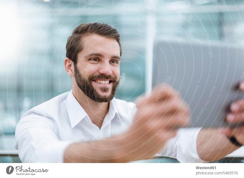 Lächelnder junger Mann macht ein Selfie mit Tablet Männer männlich lächeln Selfies Zuversicht Zuversichtlich Selbstvertrauen selbstbewusst Vertrauen