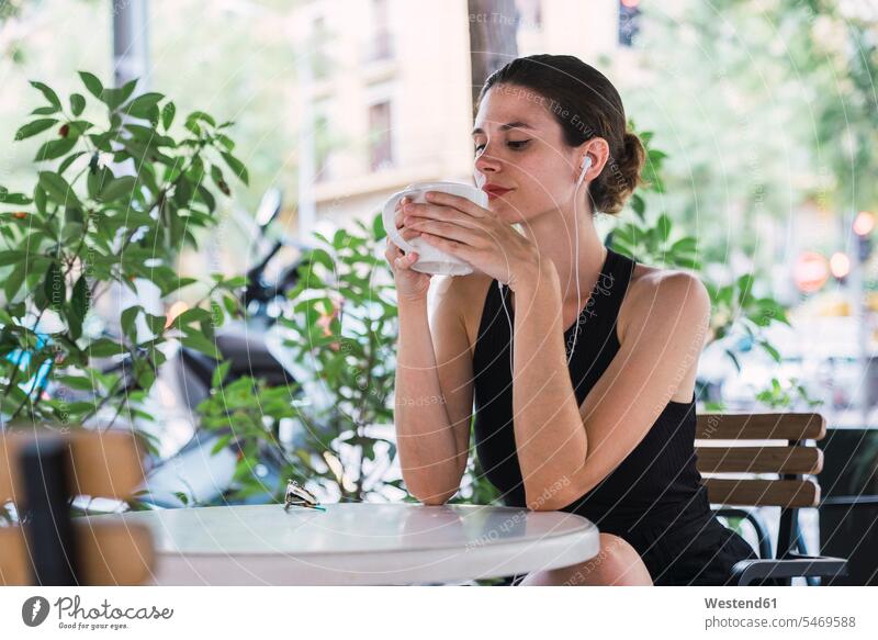 Junge Geschäftsfrau sitzt im Café, macht eine Pause, trinkt Tee sitzen sitzend Ohrhörer Musik hören Tees Geschäftsfrauen Businesswomen Businessfrauen