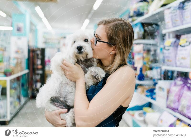 Nahaufnahme einer Pflegerin, die einen weißen West-Hochland-Terrier im Haustiersalon küsst Farbaufnahme Farbe Farbfoto Farbphoto Spanien Innenaufnahme