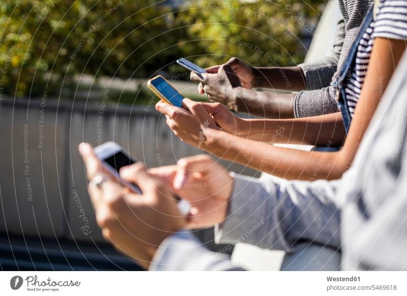Freunde, die nebeneinander stehen und Smartphones benutzen Seite an Seite aufstützen aufgestuetzt aufgestützt Geländer chatten Chat iPhone Freundschaft