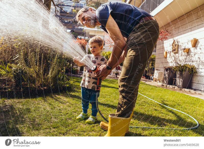 Vater und Sohn bewässern den Rasen im Garten T-Shirts Arbeit Jahreszeiten sommerlich Sommerzeit freuen Frohsinn Fröhlichkeit Heiterkeit behüten behütet geborgen