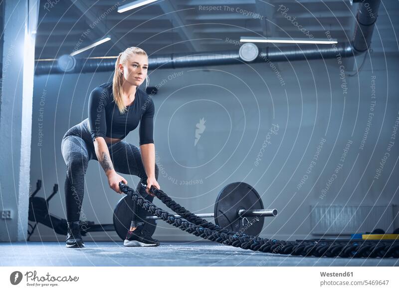 Athletische Frau trainiert mit Kampfseilen im Fitnessstudio Fitnessclubs Fitnessstudios Turnhalle weiblich Frauen sportlich Übung Uebung Übungen Uebungen Seil