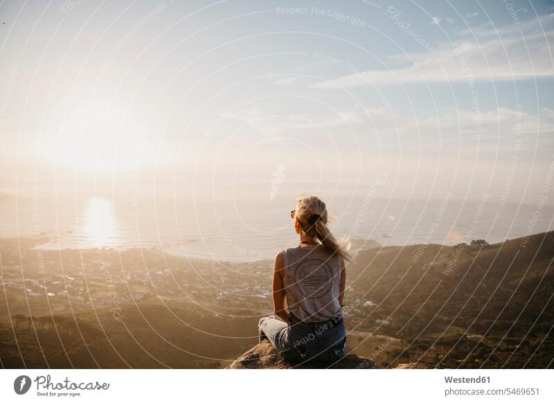 Südafrika, Kapstadt, Kloof Nek, Frau sitzt auf Felsen bei Sonnenuntergang sitzen sitzend weiblich Frauen Sonnenuntergänge Gestein Steine Erwachsener erwachsen