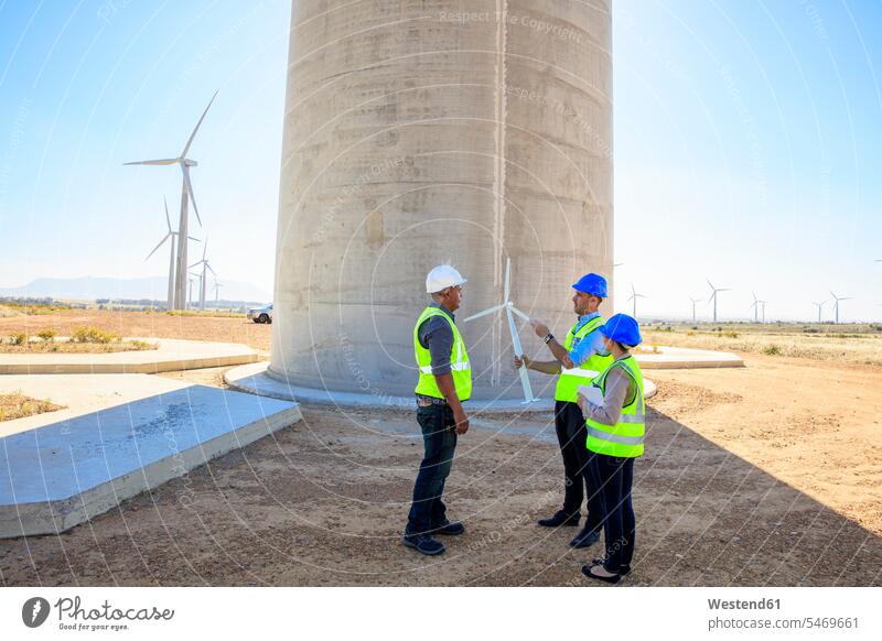 Drei Ingenieure mit Windturbinenmodell diskutieren über einen Windpark besprechen Besprechung Modell Modelle Windrad Windräder Windenergieanlage WEA WEAs