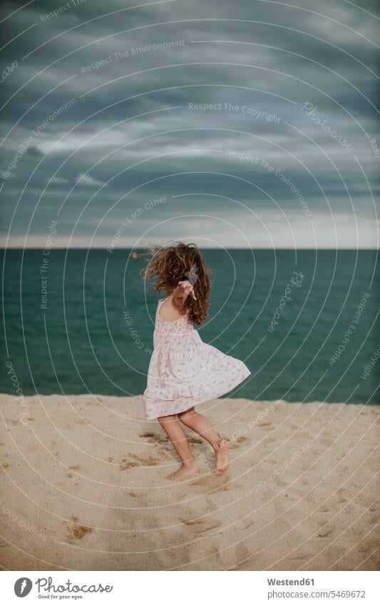 Unbeschwertes Mädchen tanzt auf Sand gegen das Meer Farbaufnahme Farbe Farbfoto Farbphoto Außenaufnahme außen draußen im Freien Abenddämmerung Dämmerung