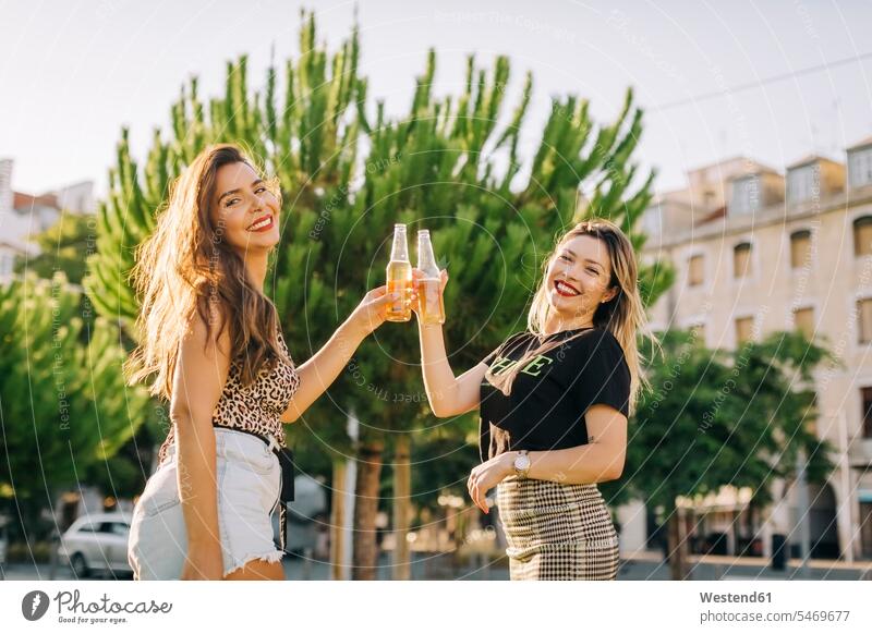 Fröhliche Freundinnen stoßen in der Stadt stehend auf Bierflaschen an Farbaufnahme Farbe Farbfoto Farbphoto Portugal Freizeitbeschäftigung Muße Zeit Zeit haben