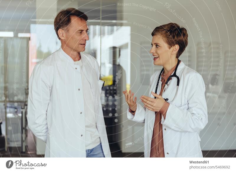 Zwei selbstbewusste Ärzte stehen in der Praxis und besprechen Arzt Doktoren lächeln Team diskutieren Besprechung Ärztin Aerztin Ärztinnen Doktorinnen Aerztinnen