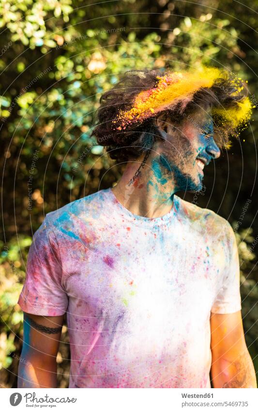 Mann schüttelt den Kopf, voll mit buntem Farbpulver, beim Feiern von Holi, dem Fest der Farben Holi-Fest den Kopf schütteln Farbpuder Puderfarbe Feste Festtag
