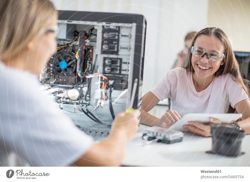 Glückliche Teenager-Mädchen, die im Unterricht Computer zusammenbauen Schule Schulen Rechner Klassenzimmer Klassenraum aufbauen Zusammenbau zusammensetzen