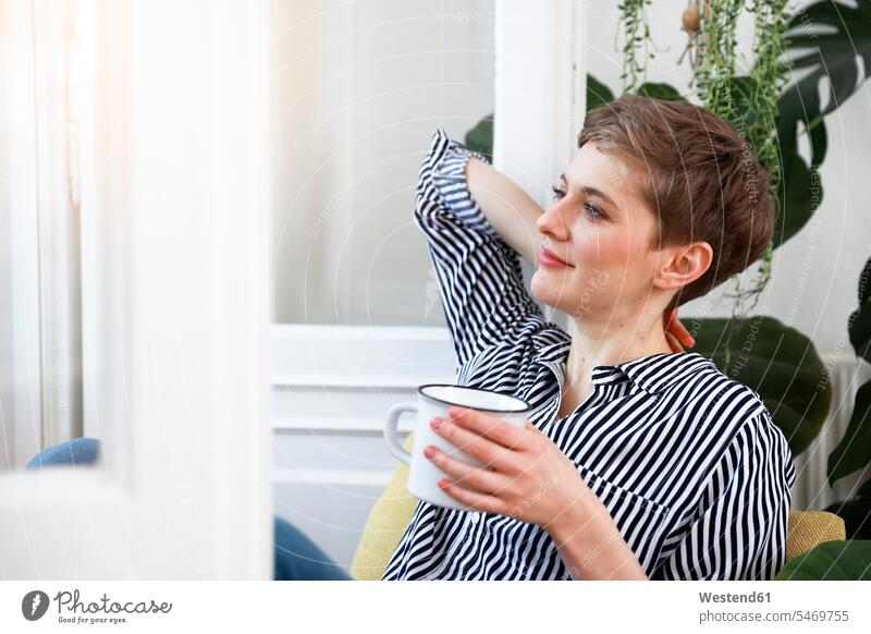 Glückliche Frau sitzt entspannt am Fenster und trinkt Kaffee entspanntheit relaxt sitzen sitzend trinken glücklich glücklich sein glücklichsein weiblich Frauen