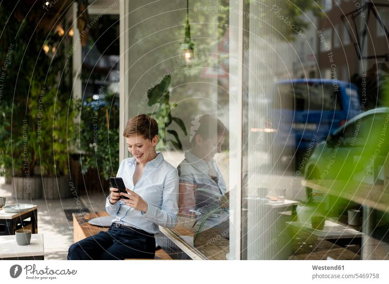 Geschäftsfrau benutzt Mobiltelefon in einem Café Leute Menschen People Person Personen Europäisch Kaukasier kaukasisch 1 Ein ein Mensch nur eine Person single