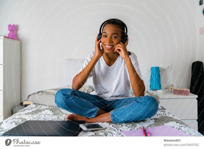 Junges Mädchen mit gekreuzten Beinen hört Musik, während sie zu Hause sitzt Farbaufnahme Farbe Farbfoto Farbphoto Innenaufnahme Innenaufnahmen innen drinnen Tag
