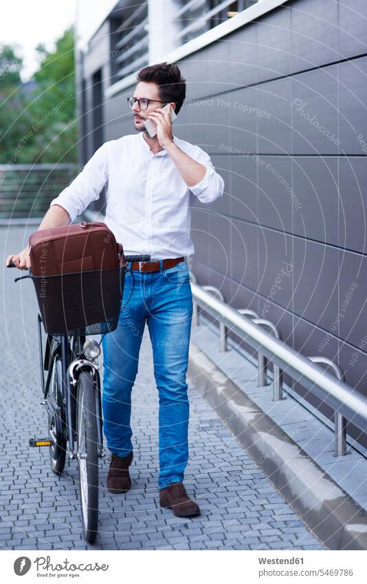 Geschäftsmann am Telefon beim Schieben seines Fahrrads schieben anschieben telefonieren anrufen Anruf telephonieren Bikes Fahrräder Räder Rad Businessmann