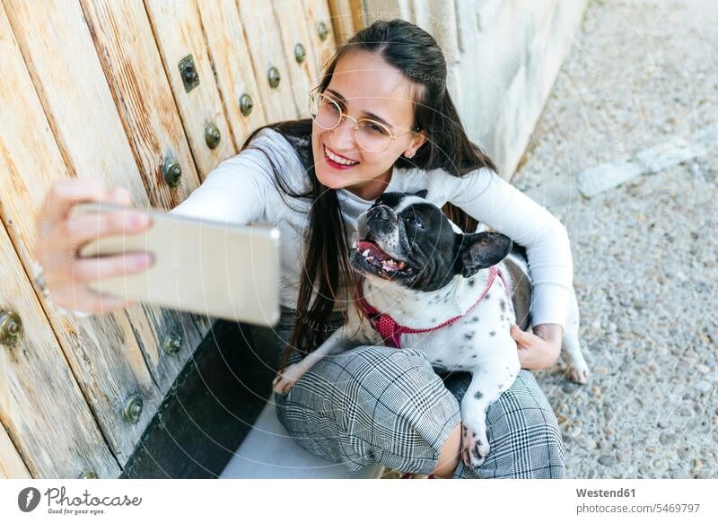 Junge Frau mit Smartphone, die ein Selfie mit ihrem Hund macht tierlieb Tierliebe Selfies iPhone Smartphones benutzen benützen fotografieren weiblich Frauen