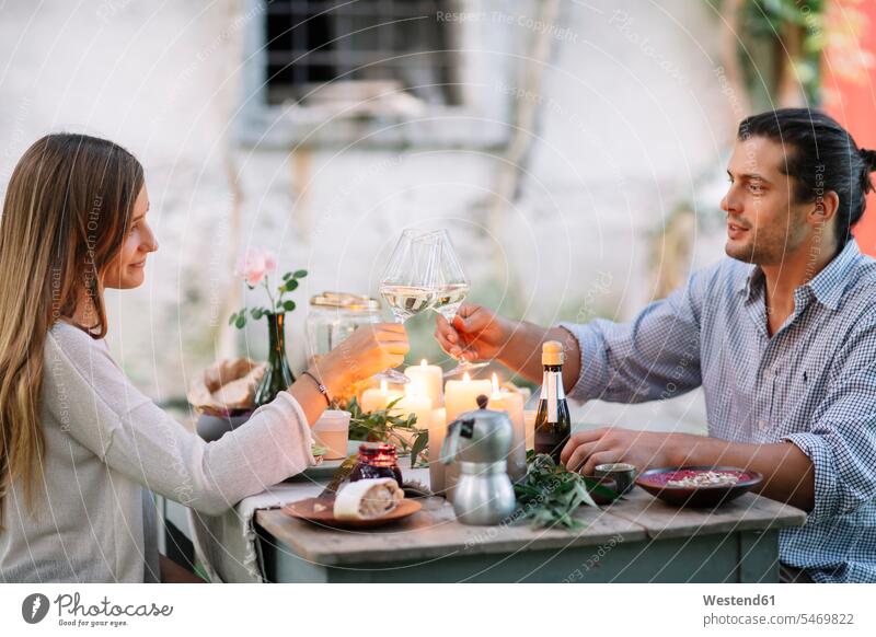 Paar mit einer romantischen Mahlzeit bei Kerzenschein klirren Weingläser Mahlzeiten Essen Speise Speisen Weinglas anstoßen zuprosten anstossen Kerzenlicht