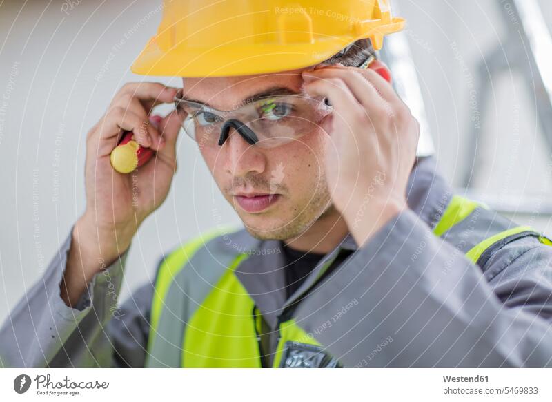 Elektriker, der eine Schutzbrille aufsetzt Schutzbrillen Brille aufsetzen Europäer Kaukasier Europäisch kaukasisch Industrie industriell Gewerbe Industrien