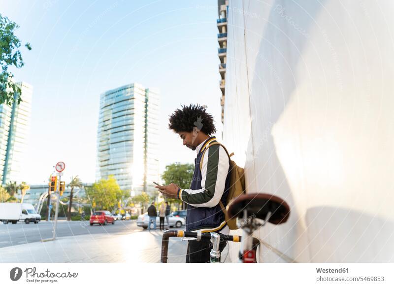 Lässiger Geschäftsmann mit Fahrrad beim Telefonieren in der Stadt, Barcelona, Spanien geschäftlich Geschäftsleben Geschäftswelt Geschäftsperson