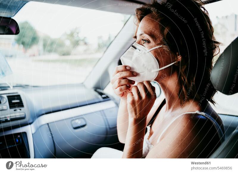 Frau trägt während COVID-19 Schutzmaske im Auto Farbaufnahme Farbe Farbfoto Farbphoto Fahrzeuginnenraum Tag Tageslichtaufnahme Tageslichtaufnahmen Tagesaufnahme