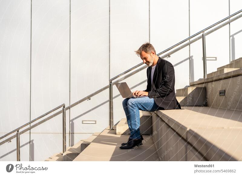 Geschäftsmann sitzt auf Stufen im Freien mit Laptop Businessmann Businessmänner Geschäftsmänner Notebook Laptops Notebooks Treppe Treppenstufe Treppenstufen