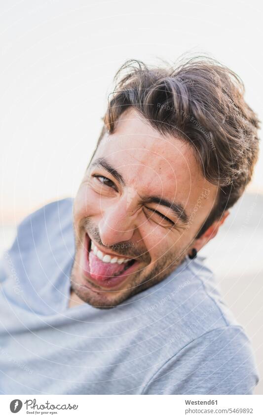 Porträt eines zwinkernden jungen Mannes, der seine Zunge herauszieht Männer männlich Portrait Porträts Portraits Zungen Erwachsener erwachsen Mensch Menschen