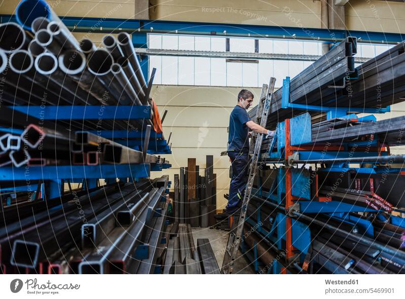 Mann arbeitet mit Metallstangen auf einem Regal in einer Fabrik Leute Menschen People Person Personen Europäisch Kaukasier kaukasisch 1 Ein ein Mensch